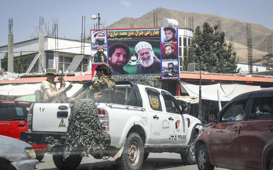 Afghan local police pass by depictions of noted anti-Taliban leaders Ahmad Shah Massoud and Burhanuddin Rabbani, July 15, 2019, as they drive through the streets of Faizabad, the provincial capital of remote Badakhshan province. The province, once a stronghold against the Taliban, fell to the militant group, Afghan officials said Aug. 11, 2021.  