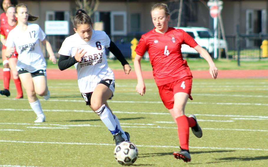 Matthew C. Perry's Sasha Malone and Nile C. Kinnick's Ainsley Rochholz chase the ball during Saturday's DODEA-Japan girls soccer match. The Red Devils won 5-0.