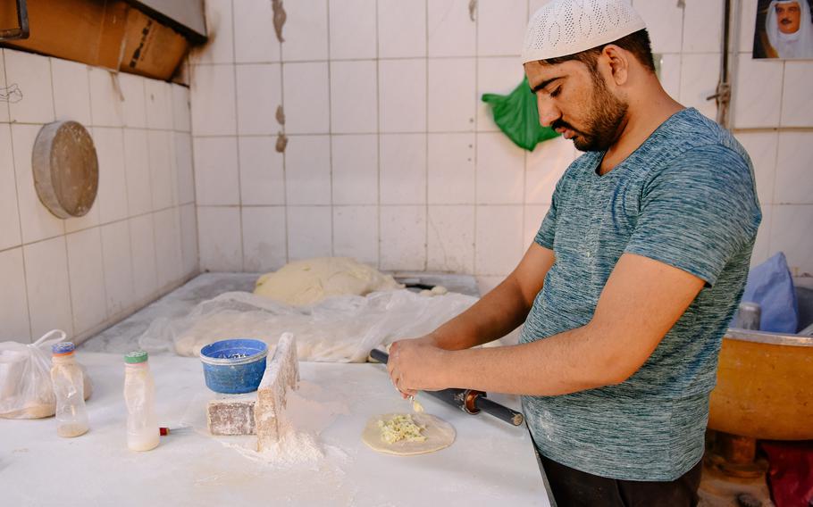 A baker in Muharraq, Bahrain, preps dough for bread before baking it in a traditional tannour oven April 28, 2024. Plain and sweet options are available.