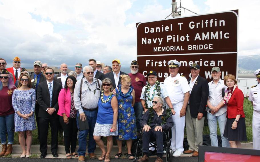 A group of people pose in front of a sign,