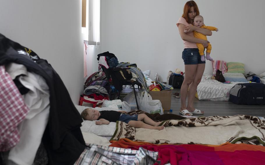 Tamara Bivalina, 31, holds her newborn son Artem, as another child sleeps in the room they are staying in at a shelter in Lviv, Ukraine on July 30. 