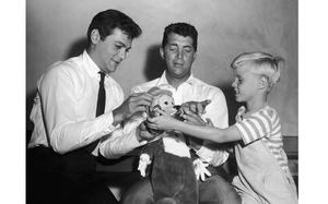 FILE - Jay North, young star of the new "Dennis the Menace" series, right, attempts to handcuff Dean Martin, center, as they play with a stuffed toy with Tony Curtis on Sept. 15, 1959. (AP Photo, File)
