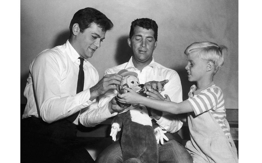 Two men and a child play with a stuffed toy