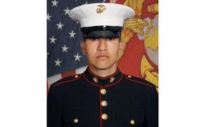Portrait of a Marine in dress uniform and hat in front of U.S. and Marine flags.