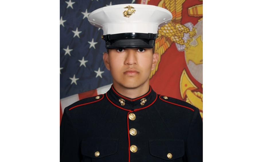Portrait of a Marine in dress uniform and hat in front of U.S. and Marine flags.