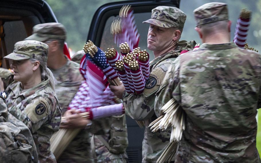 Soldiers carry American flags still wrapped up.
