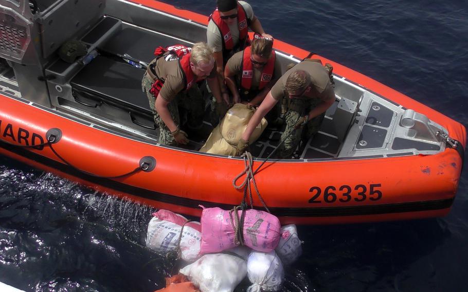 Personnel from the U.S. Coast Guard cutter Glen Harris recover bags of illegal narcotics discarded by a fishing vessel interdicted in the Gulf of Oman on May 31, 2022. 