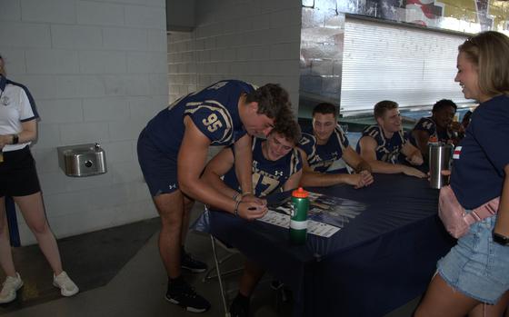 Senior defensive end Jacob Busic signs a poster at Navy Football FanFest on July 29, 2023, on the concourse of Navy-Marine Corps Memorial Stadium in Annapolis, Md.