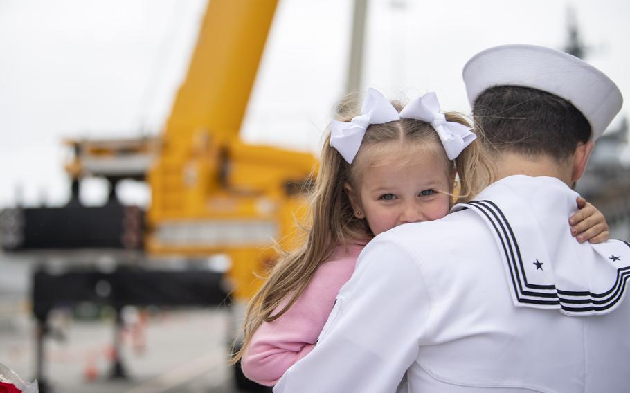 A young girl hugs a sailor
