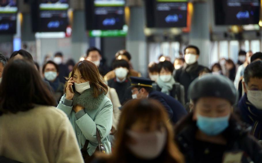Commuters make their way through Shinagawa Station in central Tokyo, Monday, Jan. 24, 2022. 