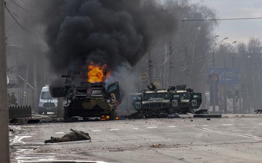 A Russian armored personnel carrier burns amid damaged and abandoned light utility vehicles after fighting in Kharkiv, Ukraine, Sunday, Feb. 27, 2022.