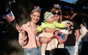A Polish family waves American flags and wears USA headbands.