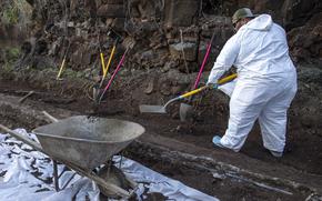 A Navy worker shovels contaminated soil into a wheelbarrow as part of a hazardous material spill recovery operation at the Red Hill fuel storage facility, Hawaii, Dec. 1, 2022.