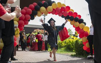 A graduate walks through a balloon arch
