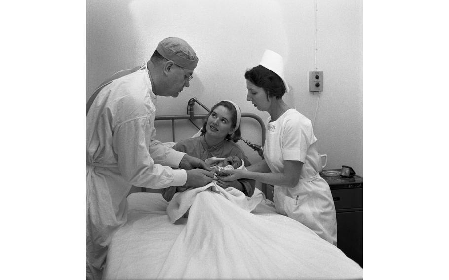 Col. Harold E. Harrison and Chief Nurse Maj. Ruth Steenburgh visit with a new mother and her baby at the 97th U.S. Army Hospital in Frankfurt. 