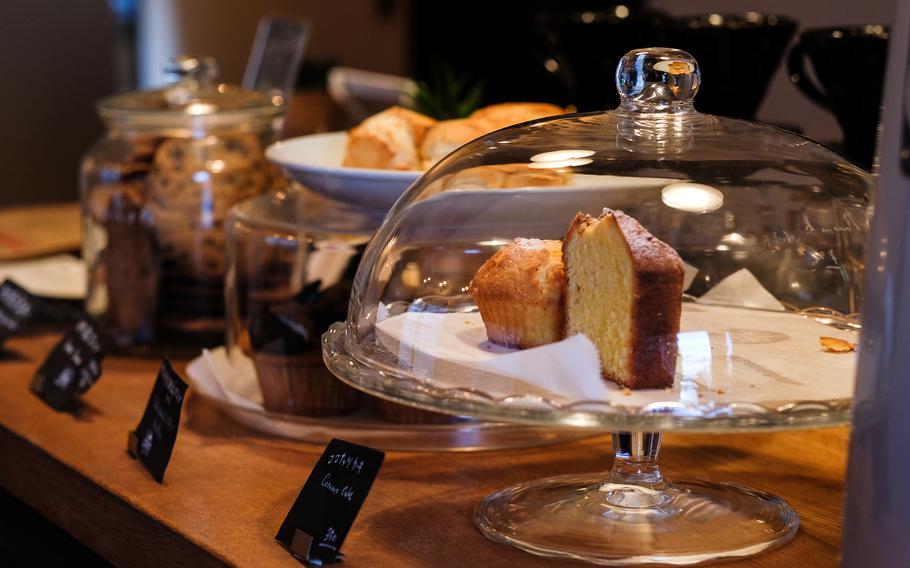 Cafe D-13's wood-finished interior, black pellet stove, reading nook, cozy rooms with seating, and displayed baked goods create a soothing atmosphere perfect for sipping coffee over a book or quietly chatting with a friend.