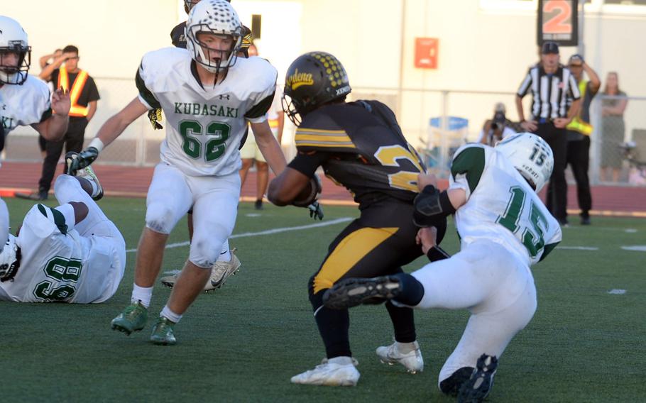 Kubasaki's Lukas Gaines gets a fistful of Kadena's Jeremiah Drummer's jersey as teammate Nicolas Jackson moves in to assist.