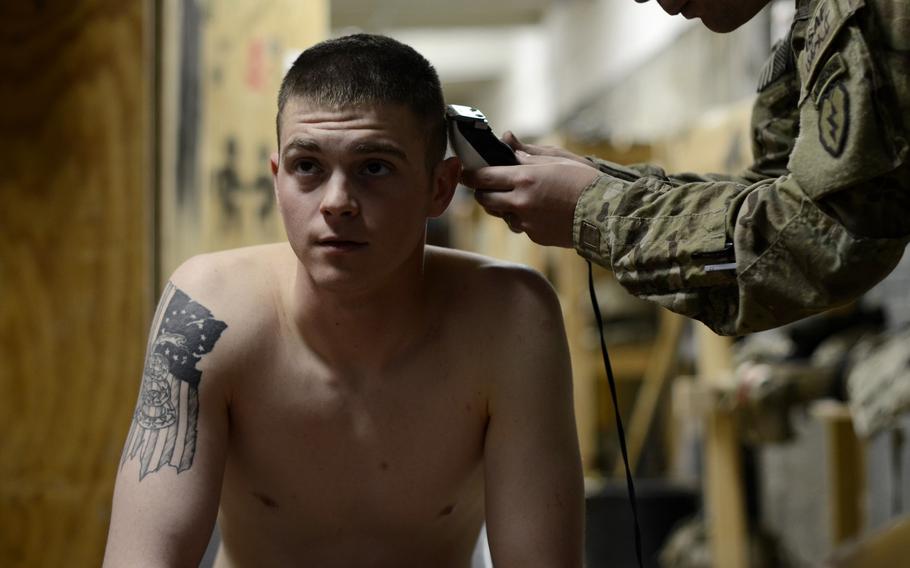 Pfc. Connor Law watches a movie while getting a haircut from Staff Sgt. John Cox in his platoon's day room at Combat Outpost Sabari, Khost province.