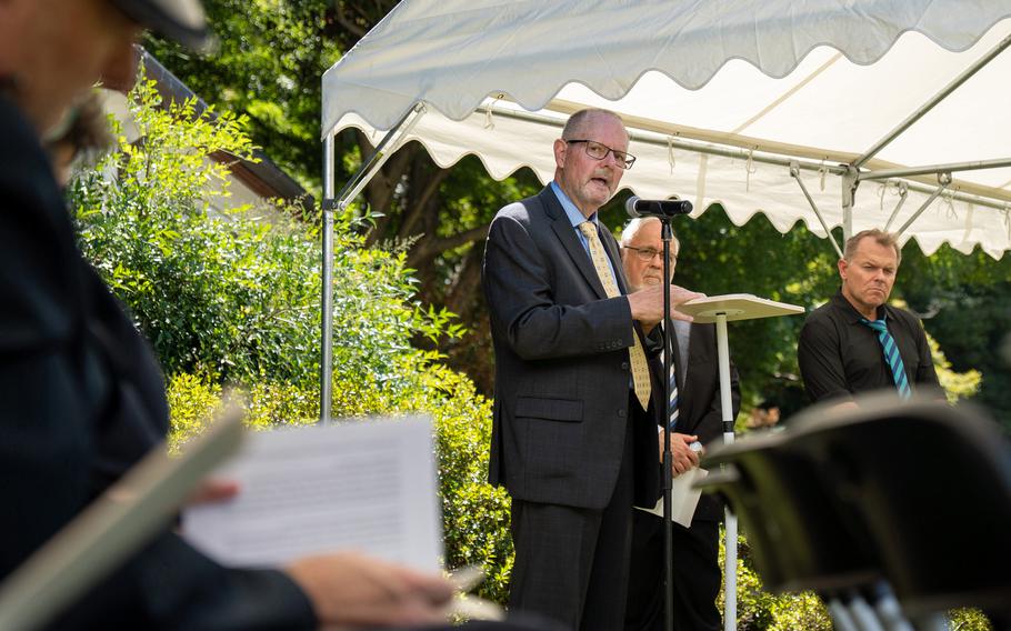 The son of a former prisoner of war speaks into a microphone during a ceremony. 