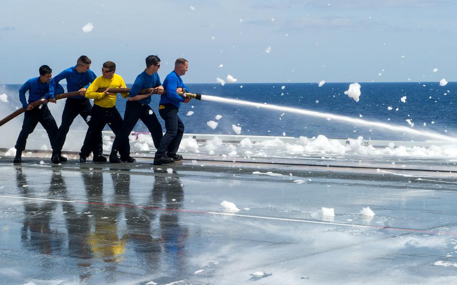 Sailors use aqueous film forming foam aboard the aircraft carrier USS Ronald Reagan during sea trials in wates south of Japan, May 12, 2018.