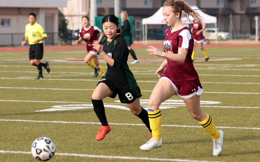 Matthew C. Perry's Patricia Perry tries to outrace Nagoya International's Sena Toyama to the ball during Friday's Western Japan Athletic Association girls soccer tournament. The Samurai won 3-1.