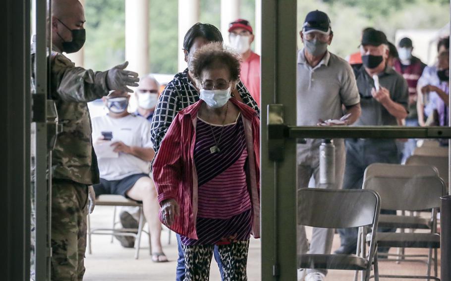 Staff Sgt. Frank Fejeran of the Guam National Guard escorts people seeking COVID-19 vaccines into Okkodo High School last year in Dededo, Guam. 