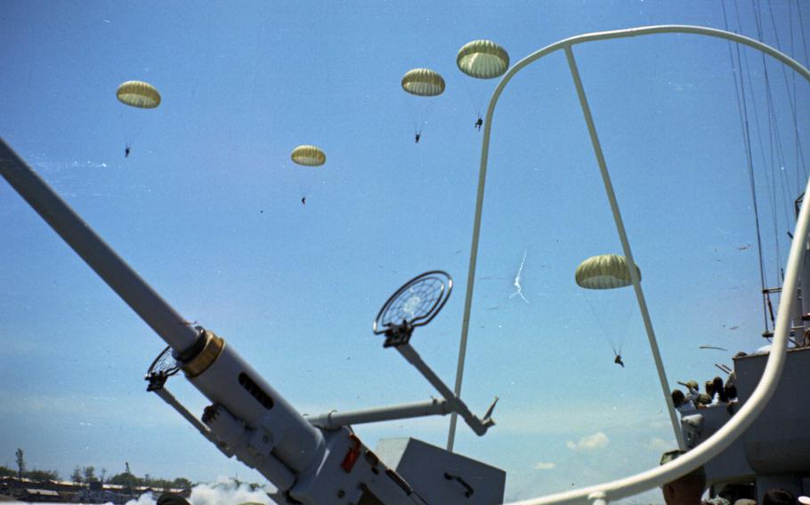 Paratroopers in the sky seen descending from the ground.