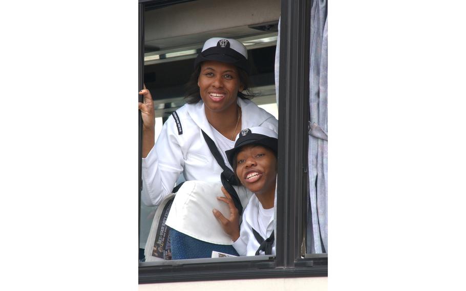 Two sailors from Carrier Airborne Early Warning Squadron One One Five, call out to friends from the bus, happy to be back home at Atsugi Naval Air Facility, Japan. The squadron was deployed for four months in support of Operation Iraqi Freedom.