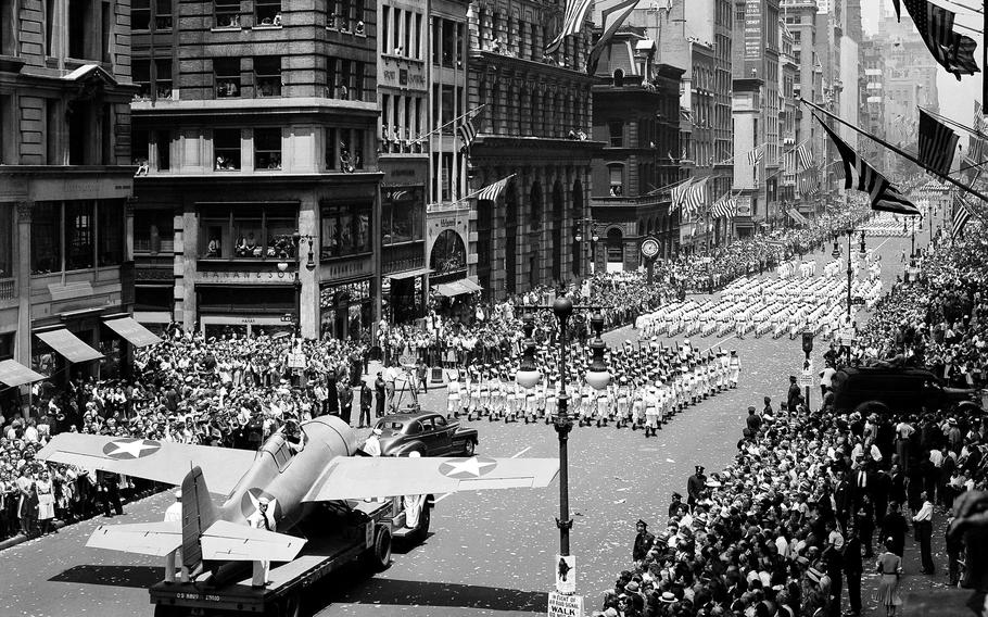 An aircraft trails behind marching troops.