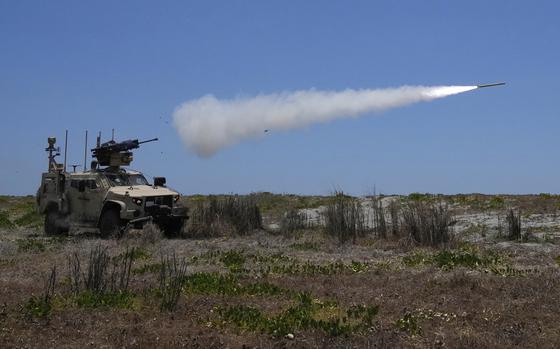 A missile fires from an armored vehicle on a field.
