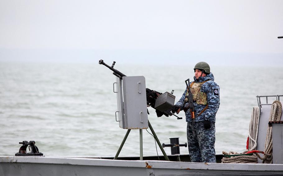 A serviceman stands guard aboard a boat patrolling an area of Ukraine’s Black Sea port of Mariupol on Feb. 11, 2022. 