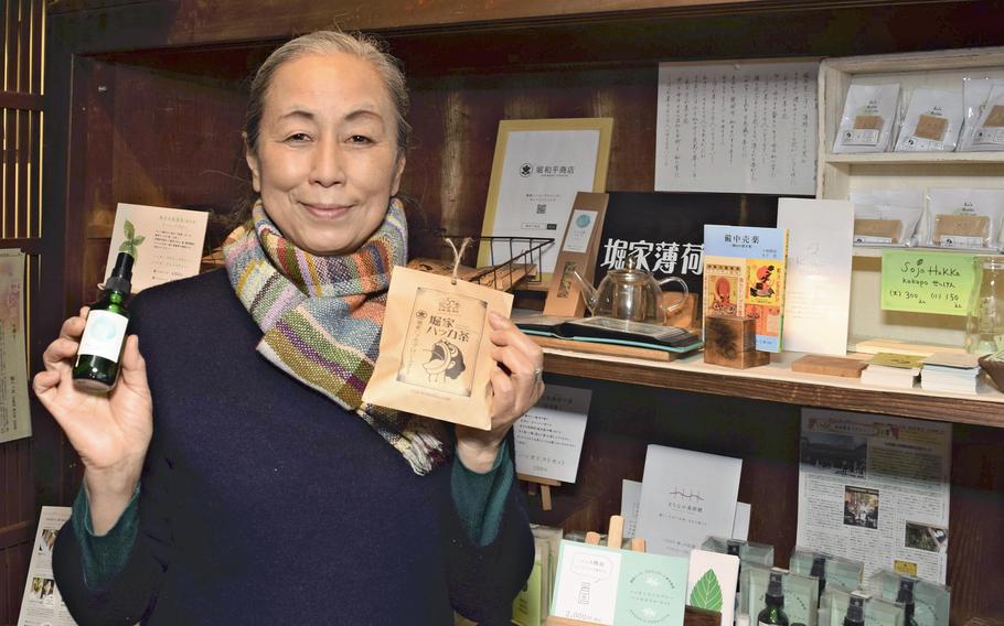 Yukiko Kanamaru of Soja, Okayama Prefecture, poses with products that use Japanese mint. 