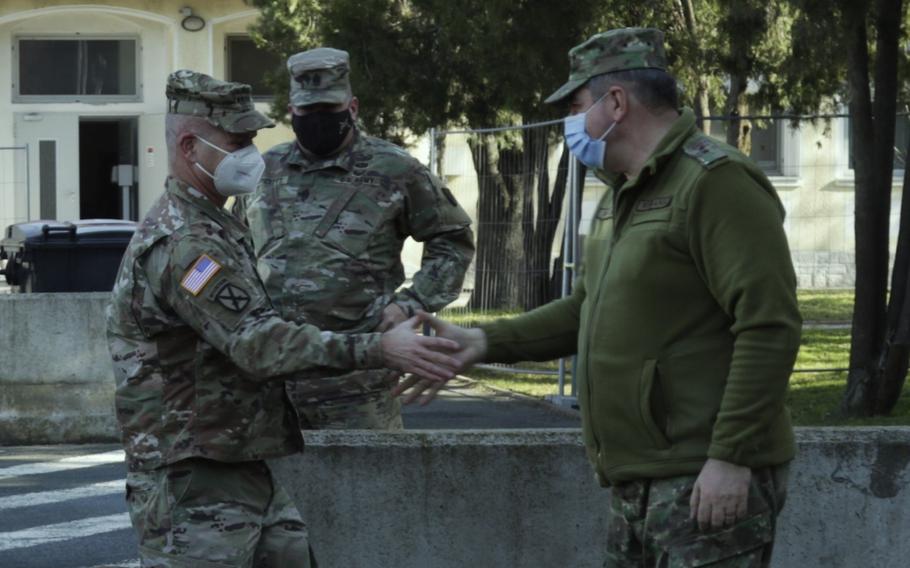 Gen. Christopher G. Cavoli, the commander of U.S. Army Europe and Africa, left, greets Maj. Gen. Iulian Berdila, the chief of the Romanian army, during a visit to Mihail Kogalniceanu Air Base, Romania, Feb. 16, 2022. Russia’s aggressive moves against Ukraine could lead NATO allies to reexamine a 1997 deal that prevents permanent basing arrangements in countries near Russia.  