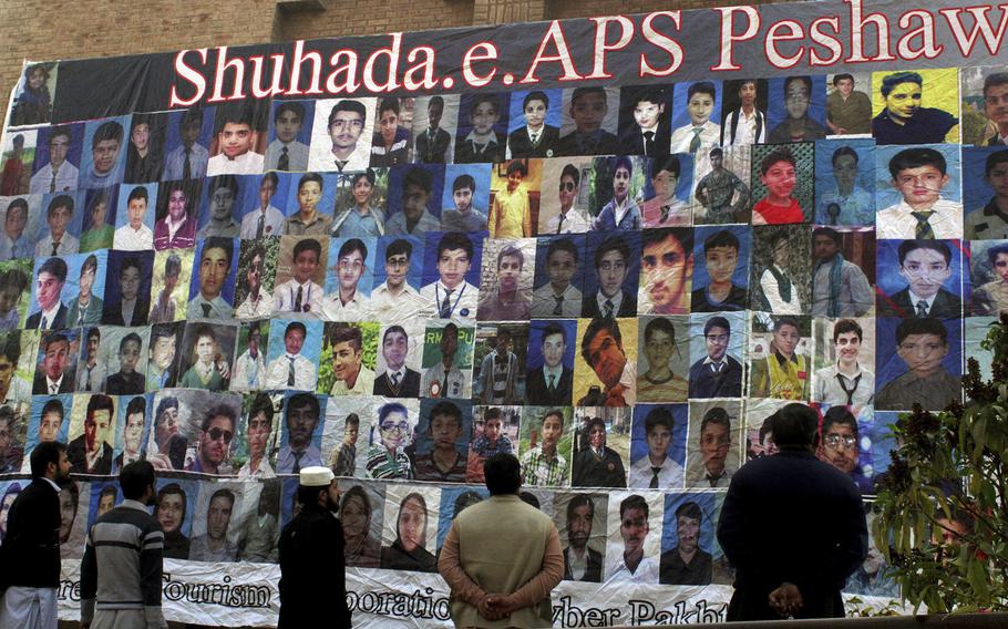Pakistanis look at a banner in Peshawar, Pakistan, Dec. 15, 2016, displaying pictures of the victims of an attack by Taliban militants on an army public school in 2014 that killed 150 people.