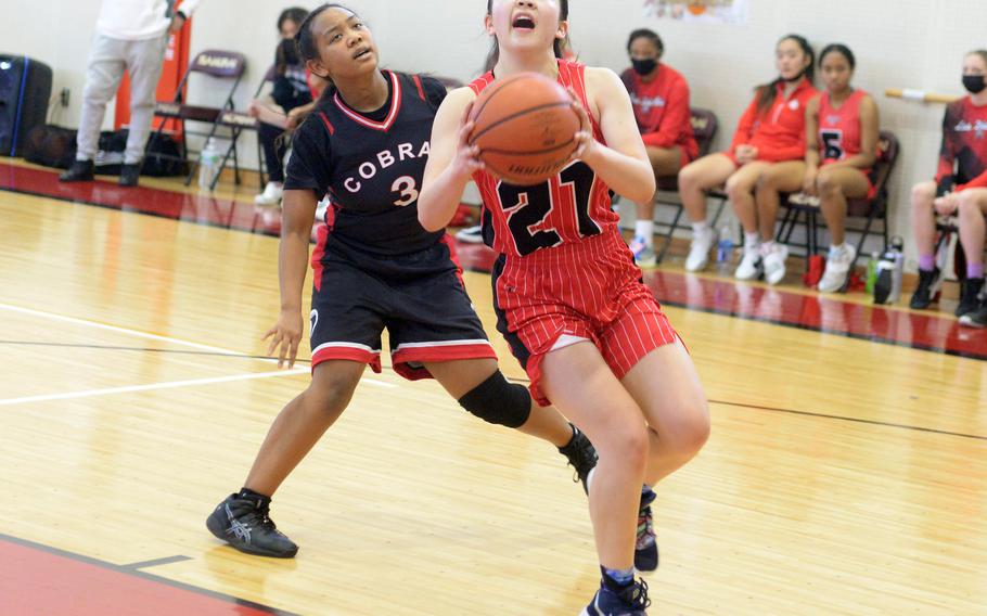 Nile C. Kinnick's Jasmine Pho drives to the basket ahead of E.J. King's Moa Best during Saturday's DODEA-Japan basketball game, which the Red Devils won 55-38.