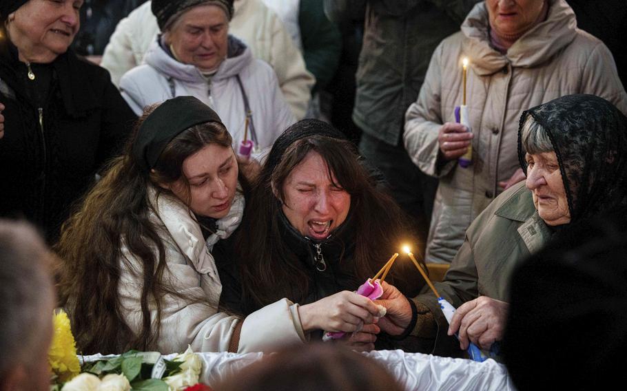 A mother cries at the coffin of her son, killed by a Russian missile.