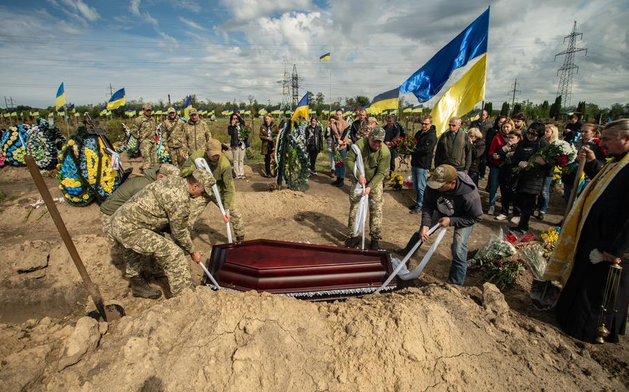 Ukrainian soldiers lower the casket of a fallen service member into a grave in Dnipro, Ukraine, Sept. 20, 2022.