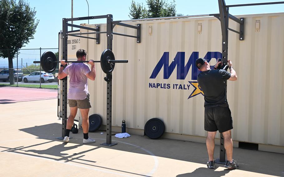 Men lift weights outside.