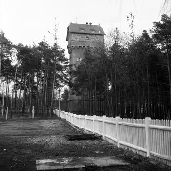A black and white photo of a tower surrounded by trees.