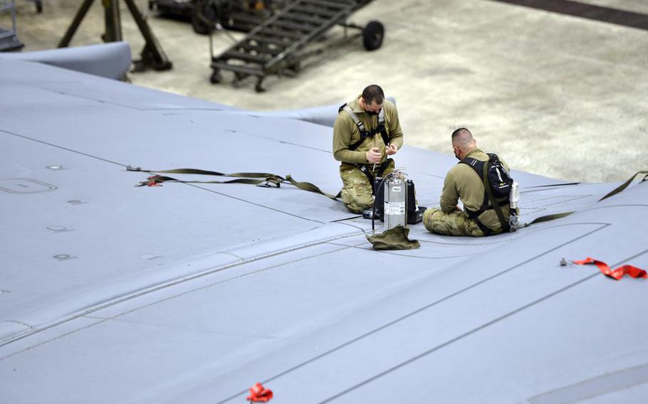 United States Air Reserve Master Sgt. Anthony Botass and Tech Sgt. Joshua Newman work high above the ground on the wing of a C-5M Super Galaxy transport plane in a maintenance hangar at Westover Air Reserve Base in Chicopee, Mass. 