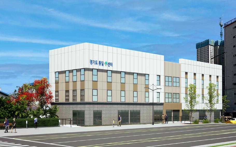 Architectural rendering of a modern three-story medical or community center building with Korean text on the facade. Large windows span all floors, and the building is surrounded by landscaping including trees with red foliage and young trees. . The scene is set in an urban environment with apartment buildings visible in the background under a partly cloudy blue sky.