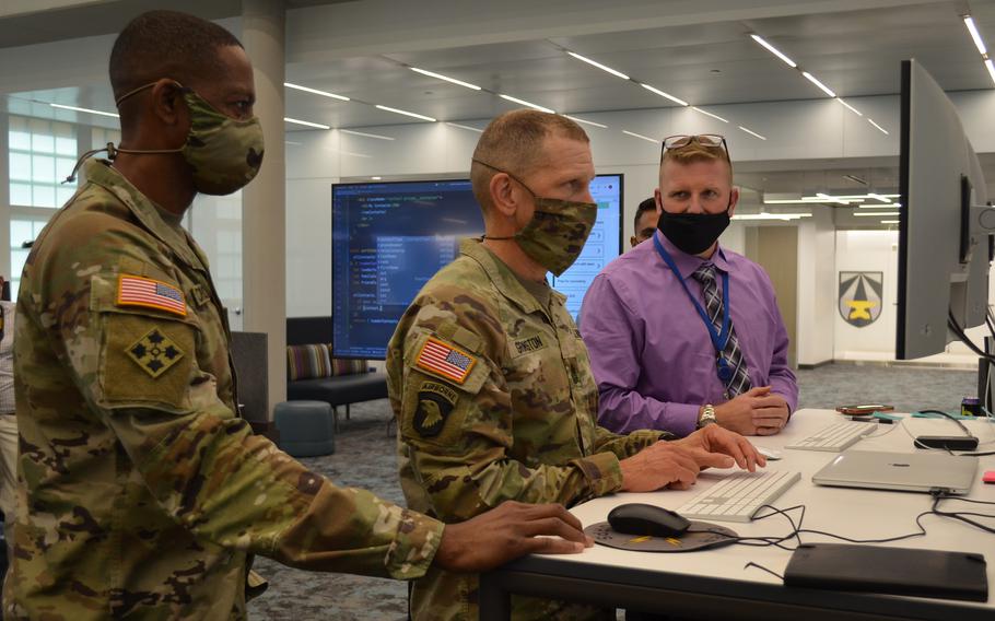 Master Sgt. Josh White, a military developer with Army Software Factory in Austin, Texas, helps Sgt. Maj. of the Army Michael Grinston, center, type script language for a smartphone app as Command Sgt. Maj. Michael Crosby, left, senior enlisted advisor for Army Futures Command, watches on Oct. 28, 2021