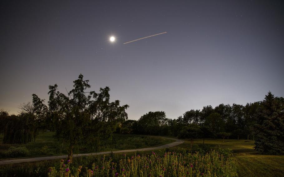 The moon above Centennial Park as an aircraft passes through the area on June 15, 2021, in Tinley Park.