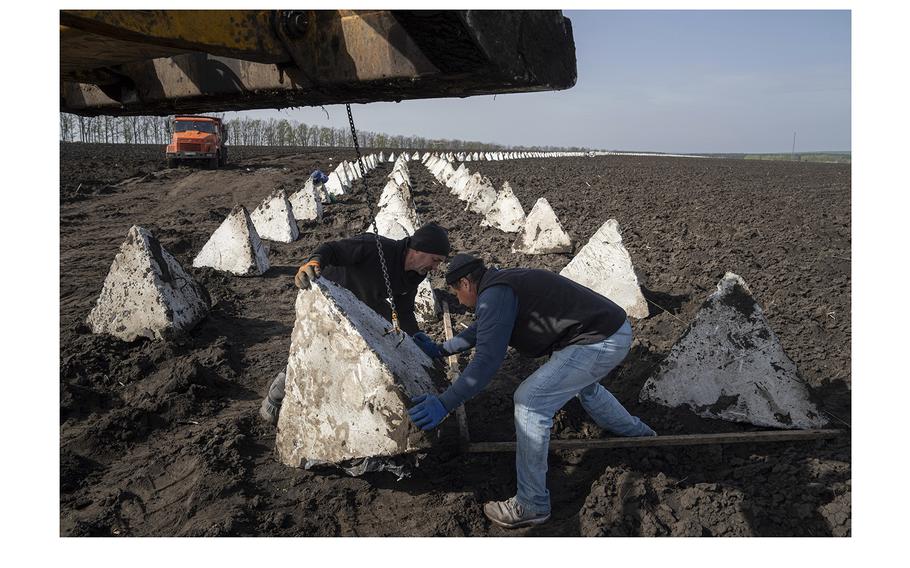 Workers install dragon teeth during the construction of new defensive positions close to the Russian border in Kharkiv region, Ukraine, on April 17, 2024. 