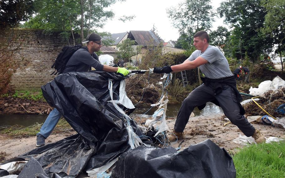 Senior Airman Calixto Rodriguez, left, and Airman Kyle Koury try to break apart a piece of debris while cleaning up the banks of the Nims River in Rittensdorf, Germany, on Saturday, July 31, 2021. 