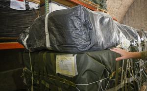 A U.S. Army parachute rigger places his hand on a bundle of humanitarian aid with a parachute on top in a warehouse at Al Udeid Air Base in Qatar, March 16, 2024.
