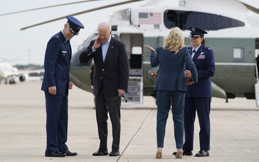 President Joe Biden brushes a cicada from his neck as he and first lady Jill Biden board Air Force One, Wednesday, June 9, 2021, at Andrews Air Force Base, Md.