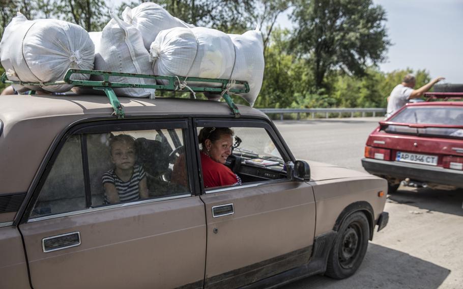 Sasha Shamlee, 7, looks out of the car window as she waits with her family in a convoy that arrived to Ukrainian-held territory outside the village of Kamiyanske, Ukraine, on Aug. 27, 2022. 