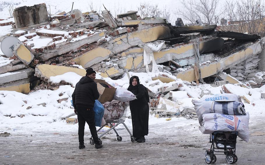 A Syrian refugee couple carry their clothes and stuffs by a shopping car in Elbistan, Turkey, on Feb. 8, 2023, two days after a 7.8-magnitude earthquake hit near Gaziantep, Turkey.