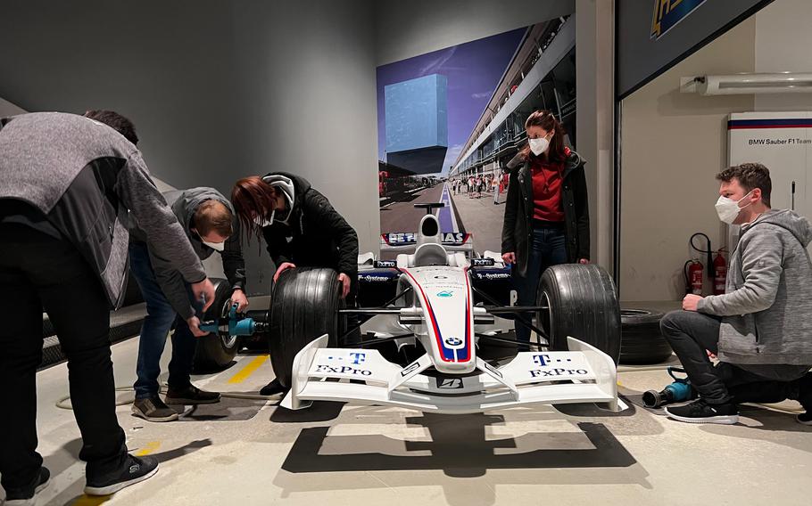 Visitors change tires on a BMW Formula 1 car at Ringwerk in Nuerburg, Germany, Jan. 15, 2022. Participants can also listen in on pit stop communication recordings and squeeze into a mock cockpit of one of the high-tech racing machines.